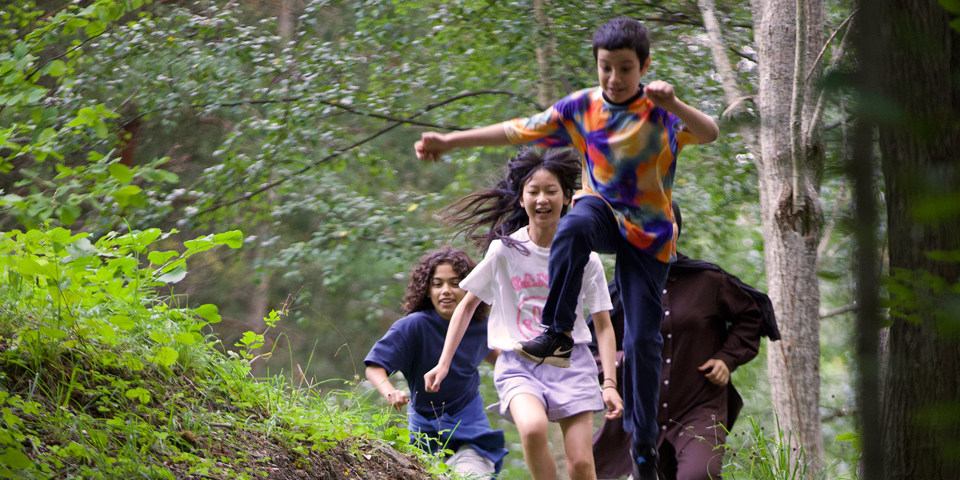 Barn som leker i en skog.